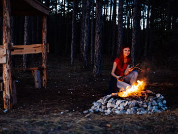 Young man sitting on log in forest