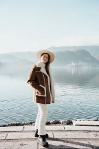 Portrait of young woman standing against lake