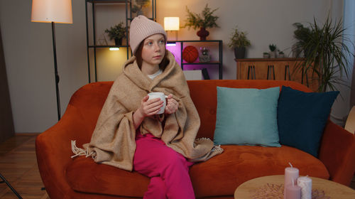 Portrait of woman sitting on sofa at home