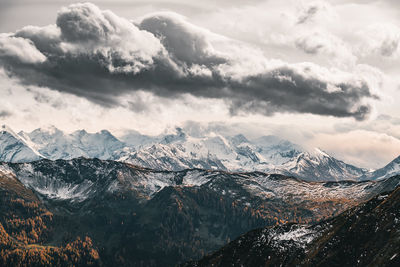 Dramatic sky over snow capped mountains in fall colors, saalbach, salzburg, austria.