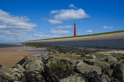 Lighthouse by sea against sky