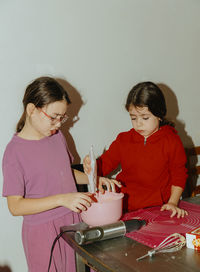 Two beautiful caucasian girls are baking cookies.