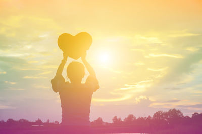 Silhouette woman standing against sky during sunset