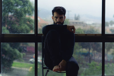 Young man looking through window