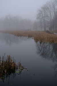 Scenic view of lake against sky during foggy weather