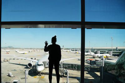 Rear view of man standing by airplane window