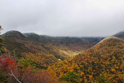 Scenic view of mountains in foggy weather against cloudy sky