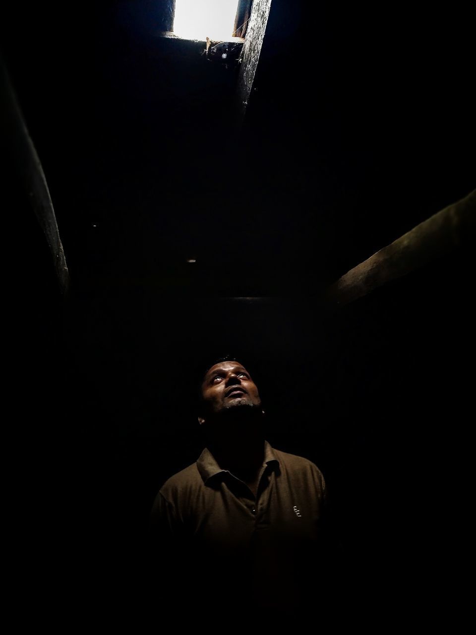 PORTRAIT OF YOUNG MAN STANDING IN DARKROOM