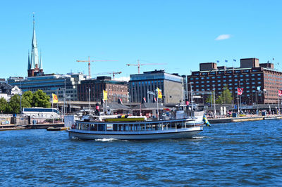 Sailboats in river against buildings in city