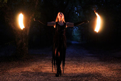 Woman with arms outstretched standing at night