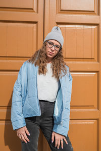 Young woman standing against yellow wall