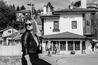 Portrait of young woman standing by building