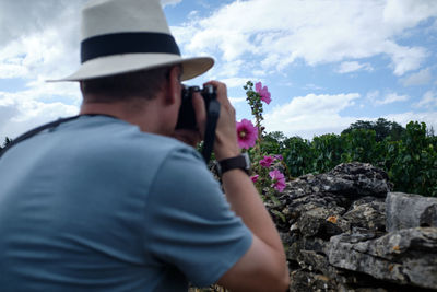 Rear view of man photographing against sky