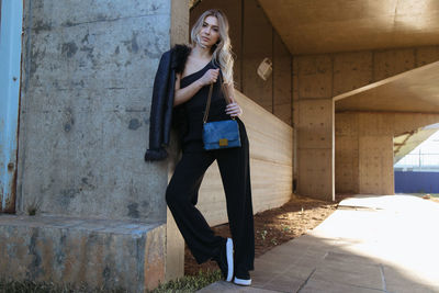 Portrait of young woman standing against wall