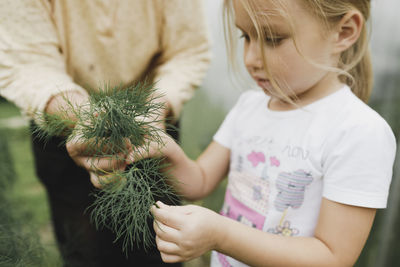 Grandmother with girl holding dill in garden