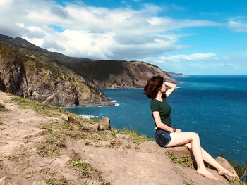 Side view of young woman against sky