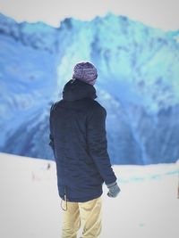 Rear view of man standing on snowcapped mountain