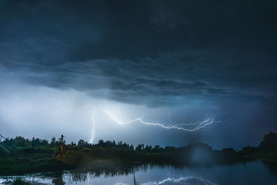 Scenic view of lightning over lake at dusk