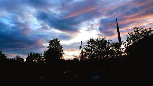 Low angle view of silhouette trees against dramatic sky