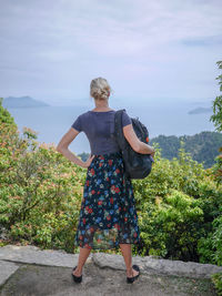 Rear view of young woman standing against trees