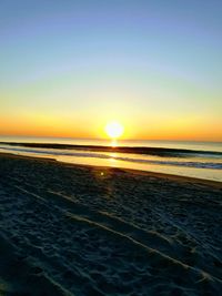 Scenic view of beach against clear sky during sunset