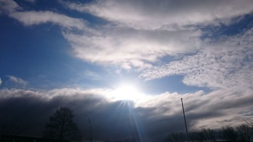 Low angle view of sun shining through clouds