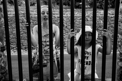 Girls seen through metallic fence