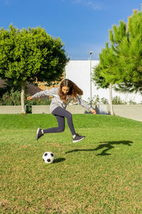 Full length of girl playing soccer ball on grass