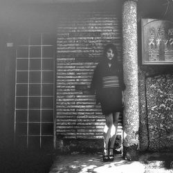 Portrait of woman standing by building