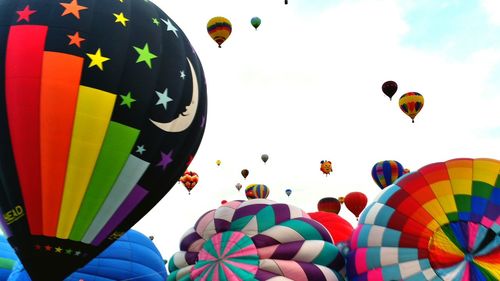 Low angle view of hot air balloons flying against sky