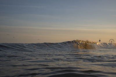 Close-up of waves rushing towards shore during sunset