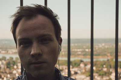 Portrait of young man sitting against railing