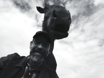 Low angle portrait of man with horse against sky