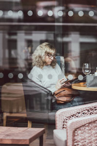 Woman using mobile phone while sitting in cafe