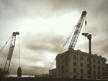 Low angle view of crane against cloudy sky