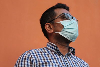 Portrait of young man wearing eyeglasses against orange background