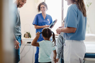 Father talking with children while healthcare workers looking at them in medical examination room