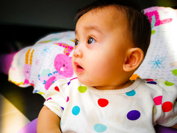 Close-up portrait of cute baby girl relaxing on bed at home