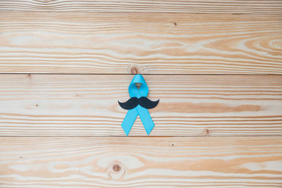 Directly above shot of aids awareness ribbon with mustache on wooden table