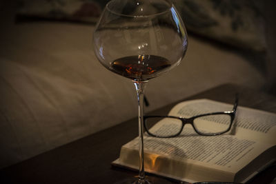 Close-up of red wine with book and glasses on table