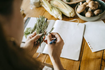 Hands of female food stylist doing quality check of rosemary herb at table