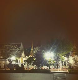 People at illuminated city against sky at night