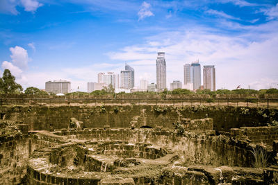 Buildings in city against cloudy sky