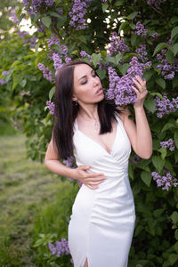 Beautiful young woman standing by flowering plants