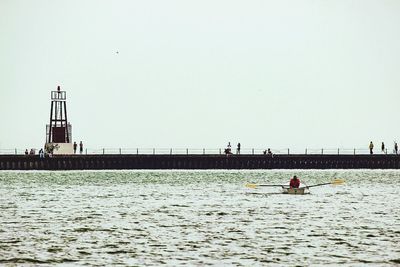 Man with nautical vessel on sea against clear sky