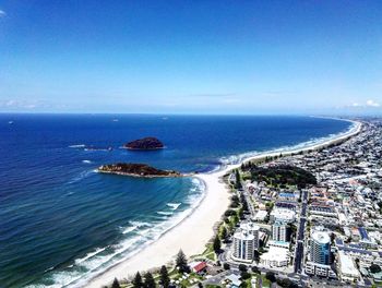 Aerial view of town by sea against blue sky