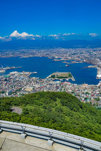 High angle view of townscape by sea against blue sky