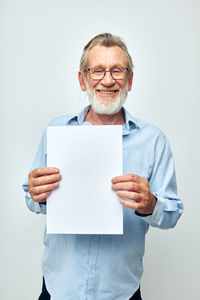 Portrait of man holding paper currency against white background