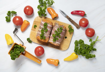 Minced meat sausages in bacon with green parsley and fresh vegetables, peppers