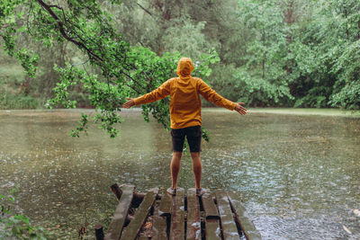 Full length of girl standing by lake in forest